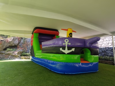 Tobogán Barco Pirata inflable - Vista 3/4 mostrando proa y tobogán en jardín exterior CDMX