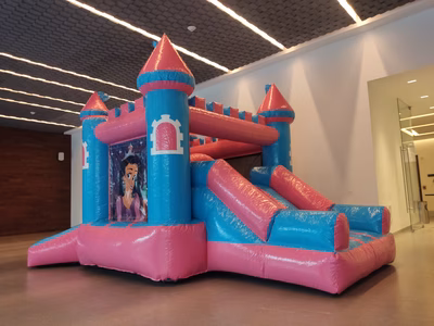 Renta inflable Castillo de Princesas CDMX - Vista frontal castillo rosa turquesa con resbaladilla en salón de eventos